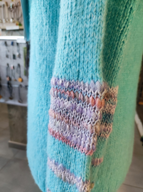 Turkusowy sweter z kolorowymi akcentami na rękawach